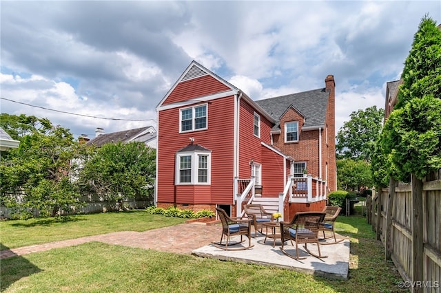 back of property with a lawn, a deck, and a patio