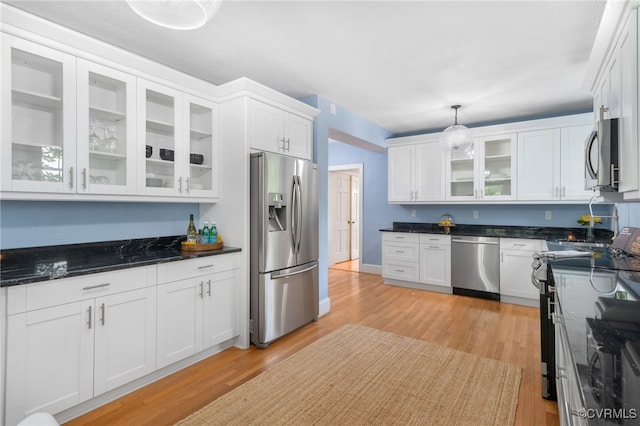 kitchen featuring white cabinets, pendant lighting, stainless steel appliances, and light hardwood / wood-style floors