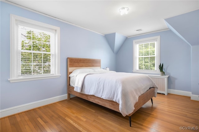 bedroom with light hardwood / wood-style flooring, vaulted ceiling, and ornamental molding