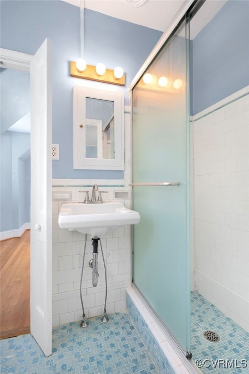 bathroom with tile patterned floors, a shower with door, and sink