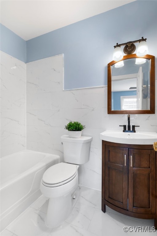 full bathroom with shower / tub combination, vanity, toilet, and tile walls