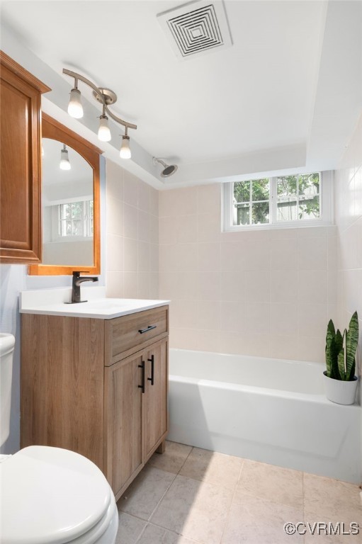 full bathroom featuring tile patterned flooring, vanity, tiled shower / bath combo, and toilet