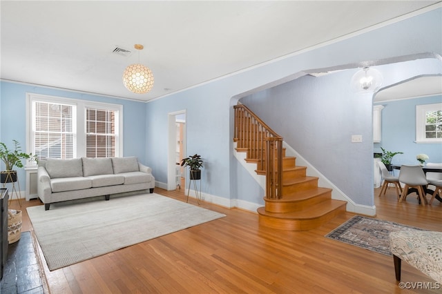 living room featuring crown molding, hardwood / wood-style floors, and a chandelier