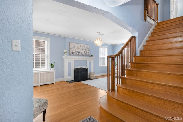 interior space featuring hardwood / wood-style floors, radiator heating unit, crown molding, and a brick fireplace