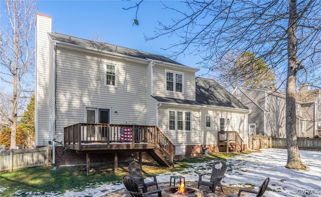 snow covered back of property featuring an outdoor fire pit and a wooden deck