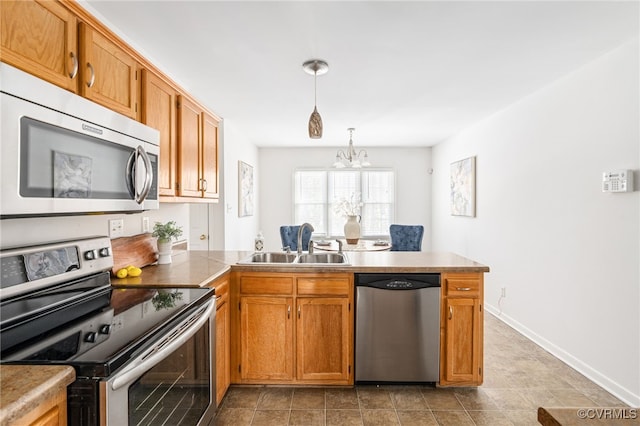 kitchen with kitchen peninsula, a chandelier, hanging light fixtures, appliances with stainless steel finishes, and sink