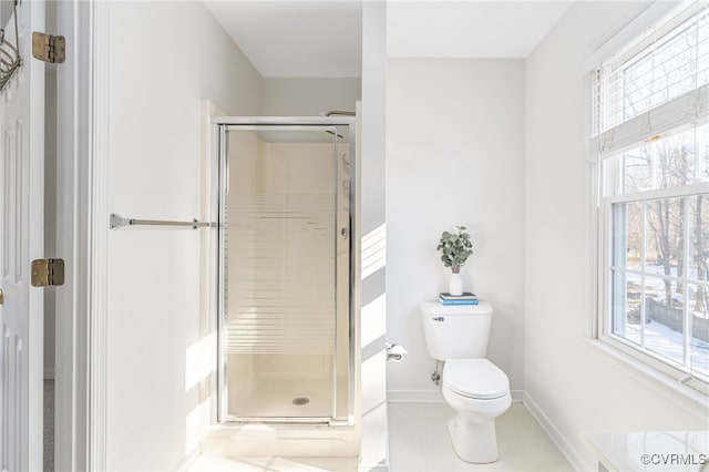 bathroom featuring a shower with door, a wealth of natural light, and toilet