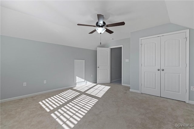 unfurnished bedroom with lofted ceiling, ceiling fan, a closet, and light carpet