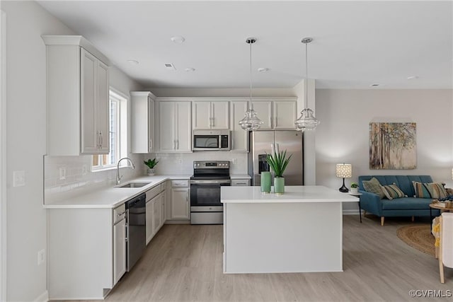 kitchen featuring pendant lighting, backsplash, sink, white cabinetry, and stainless steel appliances