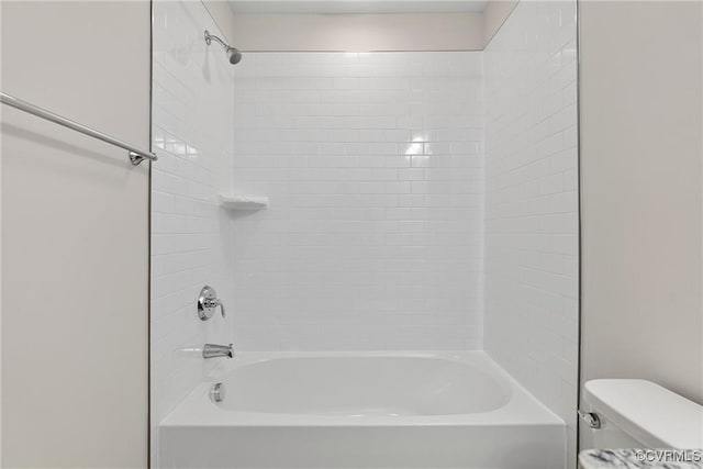 bathroom featuring tiled shower / bath combo and toilet