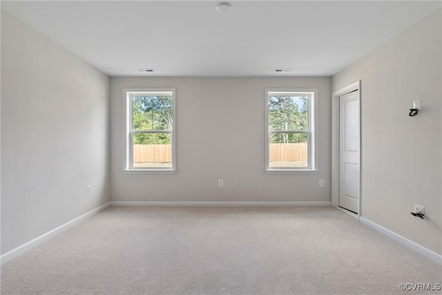 unfurnished room with light colored carpet and a healthy amount of sunlight