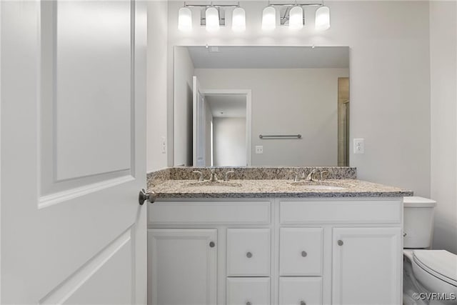 bathroom featuring vanity, a shower with shower door, and toilet