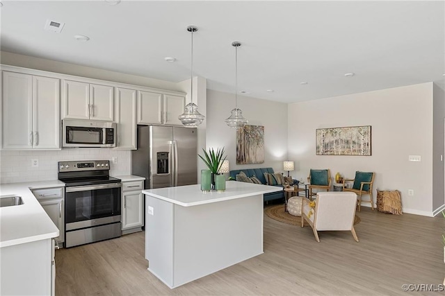 kitchen with pendant lighting, a center island, white cabinetry, and appliances with stainless steel finishes