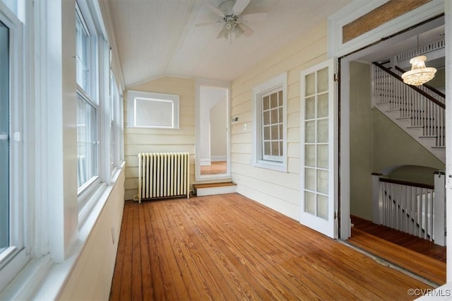 unfurnished sunroom with lofted ceiling, radiator, and ceiling fan with notable chandelier