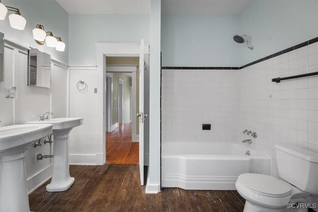 bathroom featuring a tub to relax in, baseboards, toilet, and wood finished floors