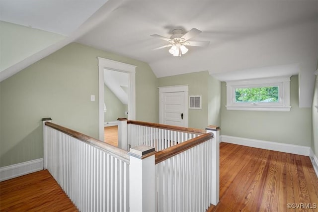 corridor featuring visible vents, vaulted ceiling, an upstairs landing, wood finished floors, and baseboards