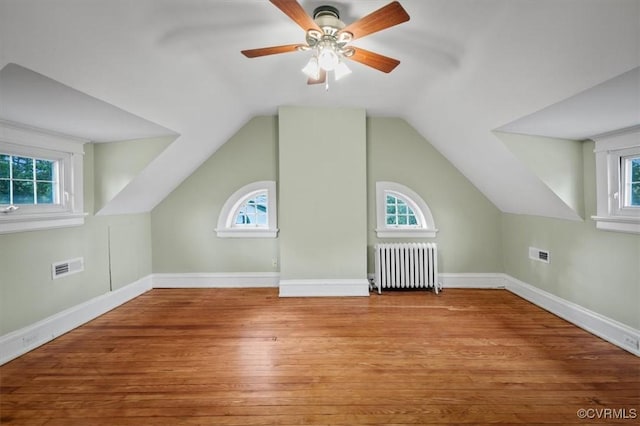 bonus room with baseboards, visible vents, radiator heating unit, and wood finished floors