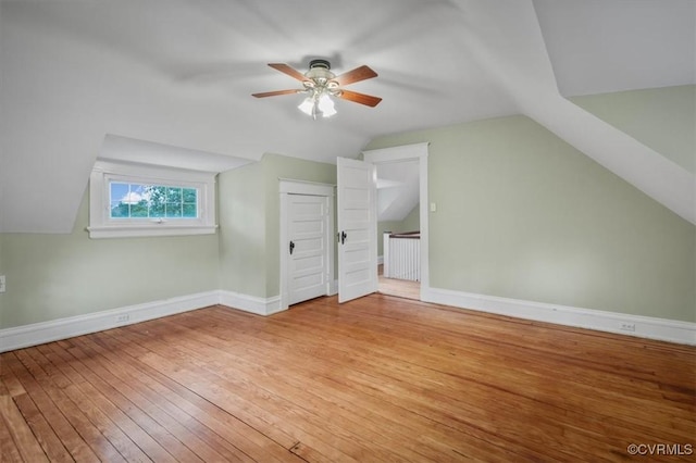 additional living space with lofted ceiling, light wood-style flooring, baseboards, and a ceiling fan