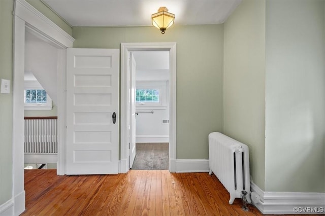 interior space with radiator heating unit, wood-type flooring, and baseboards