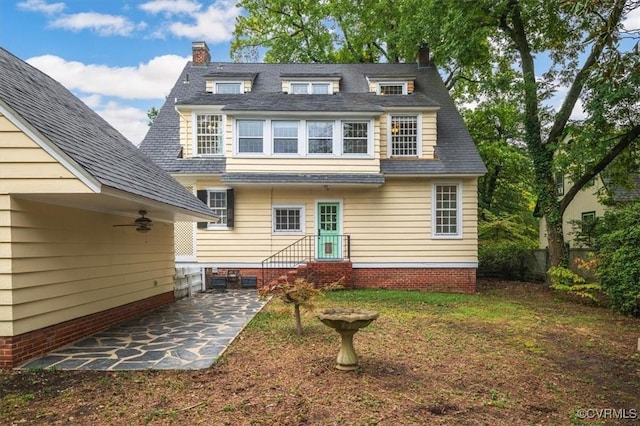 back of property with a patio, a lawn, and a chimney
