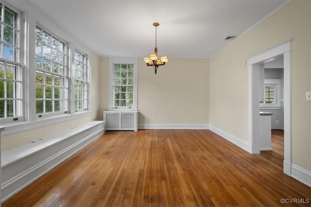 spare room with radiator, hardwood / wood-style floors, baseboards, and a notable chandelier