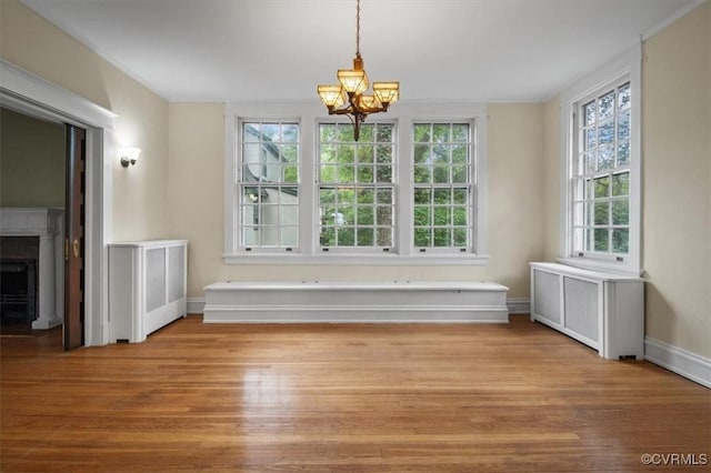 unfurnished dining area featuring a chandelier, light wood-style flooring, and radiator heating unit