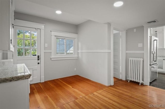 interior space with visible vents, recessed lighting, light wood-style flooring, and radiator