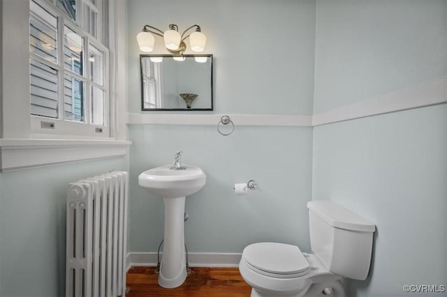 bathroom with radiator, baseboards, toilet, and wood finished floors