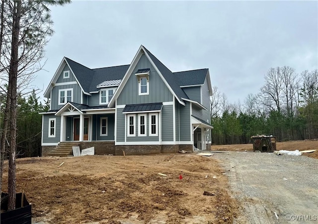 view of front of property with driveway, a standing seam roof, covered porch, board and batten siding, and metal roof