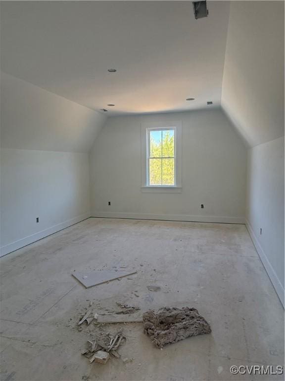 additional living space with baseboards and vaulted ceiling