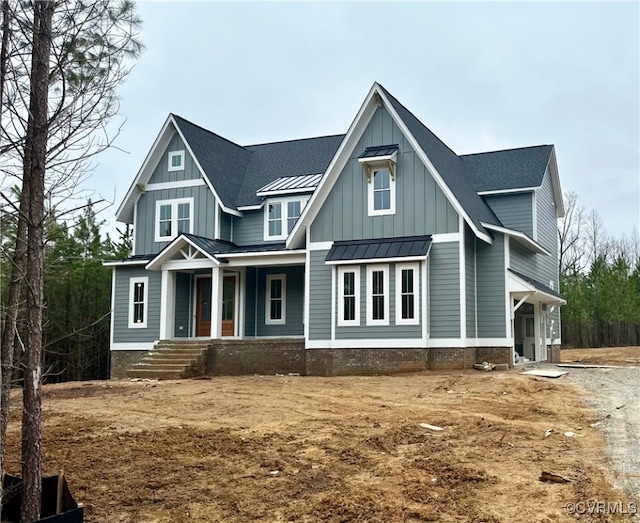 view of front of house with board and batten siding, a shingled roof, covered porch, metal roof, and a standing seam roof