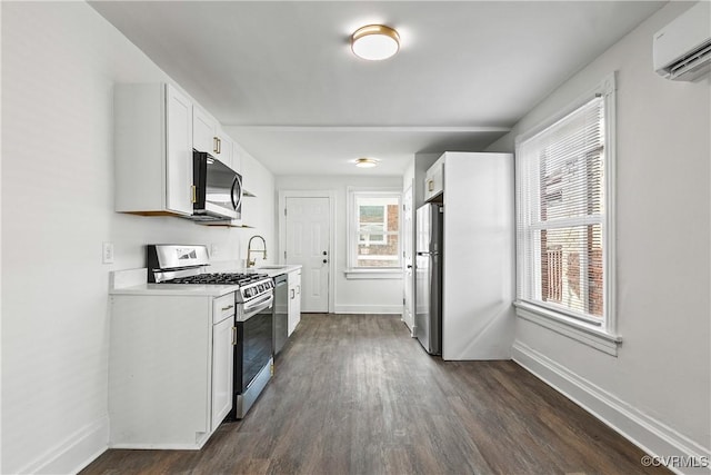 kitchen featuring sink, appliances with stainless steel finishes, a wall mounted AC, dark hardwood / wood-style flooring, and white cabinetry