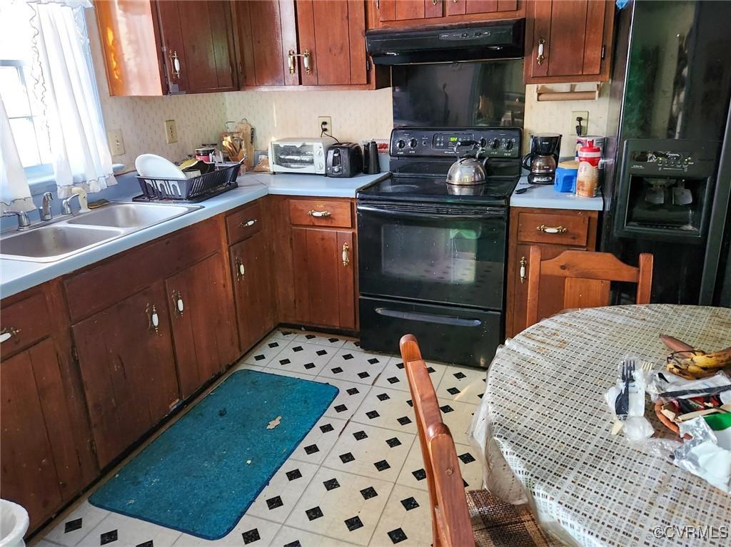 kitchen with black appliances, light tile patterned floors, and sink