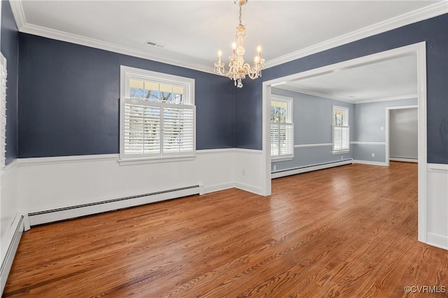 empty room featuring baseboard heating, ornamental molding, and wood-type flooring