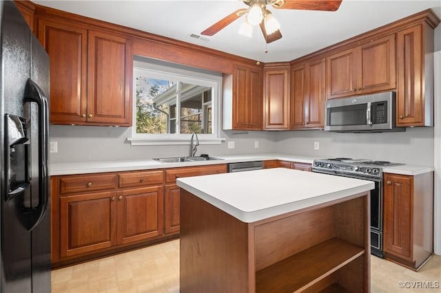 kitchen featuring ceiling fan, sink, a center island, and stainless steel appliances