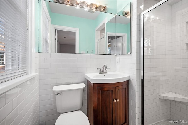 bathroom featuring tile walls, toilet, a shower with door, and vanity