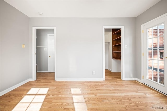 unfurnished bedroom with a closet, a spacious closet, and light hardwood / wood-style flooring