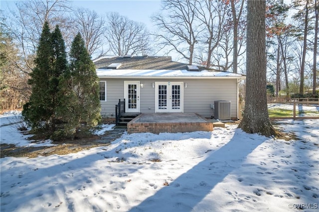 snow covered property featuring central AC and french doors