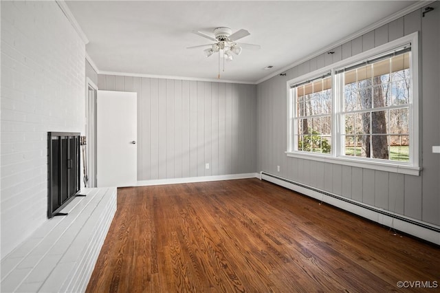 unfurnished living room with a brick fireplace, crown molding, wood-type flooring, and a baseboard radiator