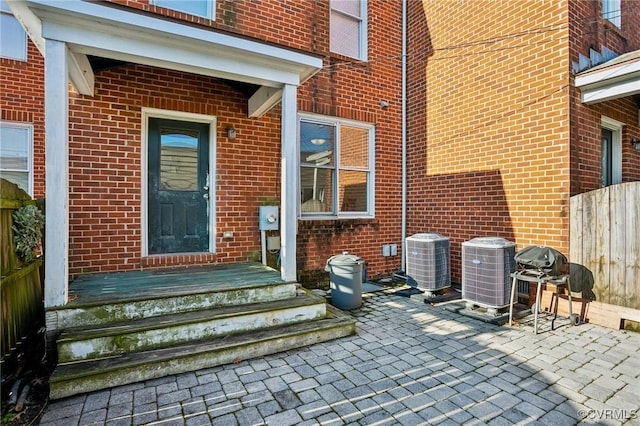 view of exterior entry with a patio area and central air condition unit