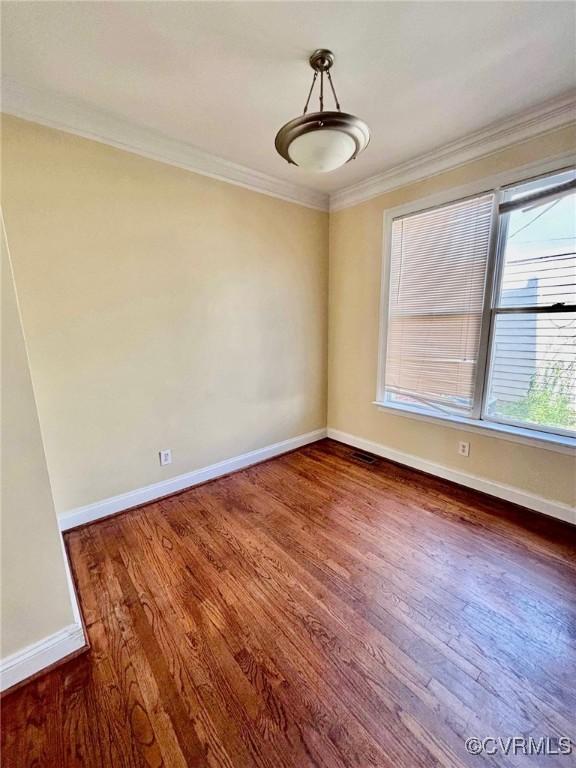 spare room with dark wood-type flooring and ornamental molding