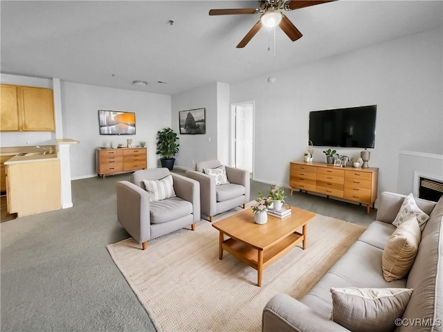 living room with ceiling fan, light colored carpet, and a fireplace