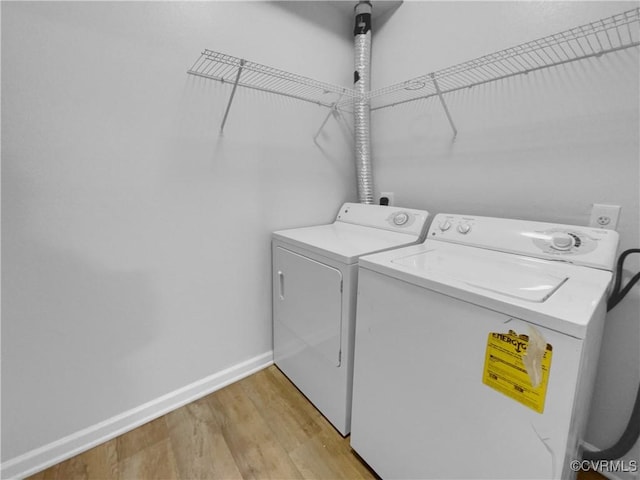 laundry room featuring washing machine and clothes dryer and light hardwood / wood-style flooring