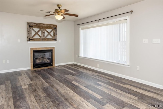 unfurnished living room with ceiling fan, a tiled fireplace, and dark hardwood / wood-style flooring