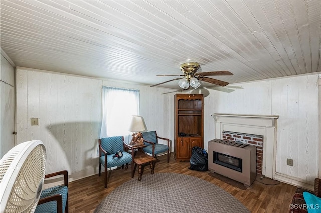 living area with ceiling fan, wood walls, hardwood / wood-style flooring, heating unit, and wood ceiling