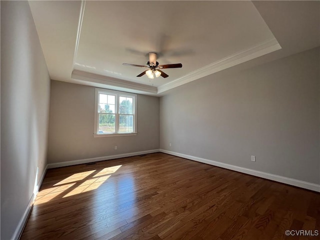 unfurnished room featuring dark hardwood / wood-style floors, ceiling fan, and a tray ceiling