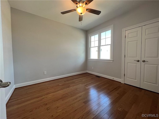 unfurnished bedroom with dark wood-type flooring, ceiling fan, and a closet