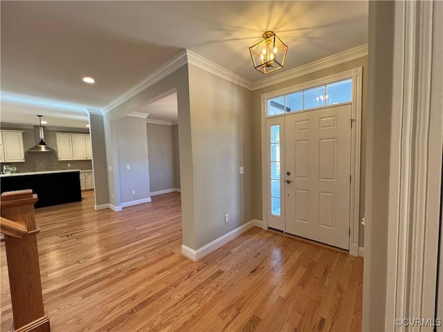 foyer entrance featuring ornamental molding, light hardwood / wood-style floors, and a chandelier