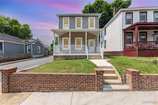 view of front of home with a porch and a lawn