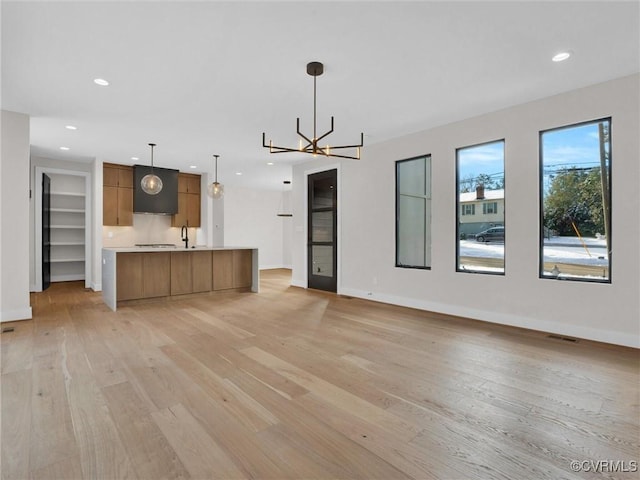 unfurnished living room featuring light hardwood / wood-style flooring and a chandelier